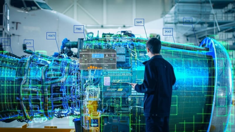 Engineer stands in futuristic factory looking at a 3D model of an airplane engine while holding digital tablet