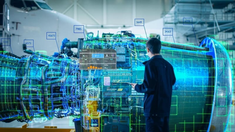 Engineer stands in futuristic factory looking at a 3D model of an airplane engine while holding digital tablet