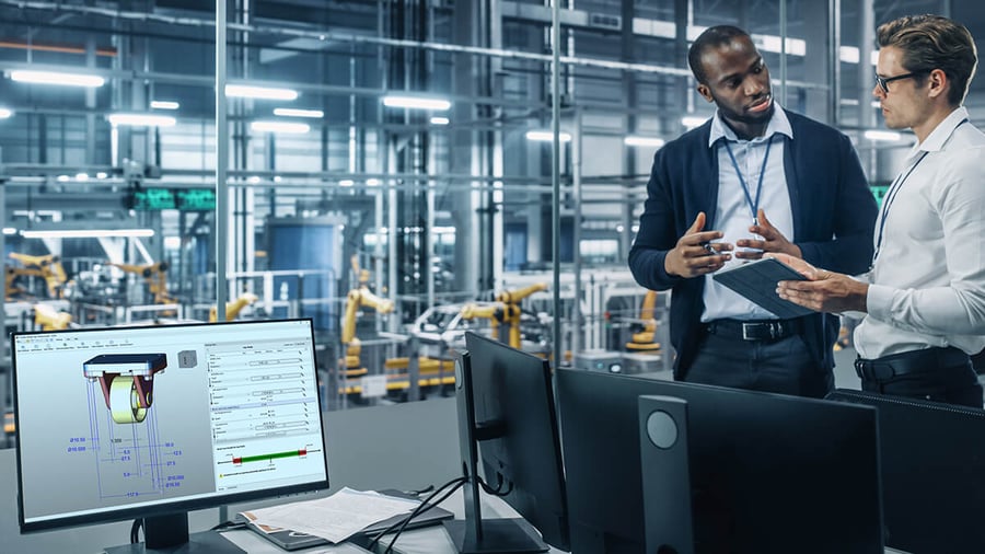 Two male engineerings having a conversation with desktop computer with Sigmetrix EZtol software in foreground